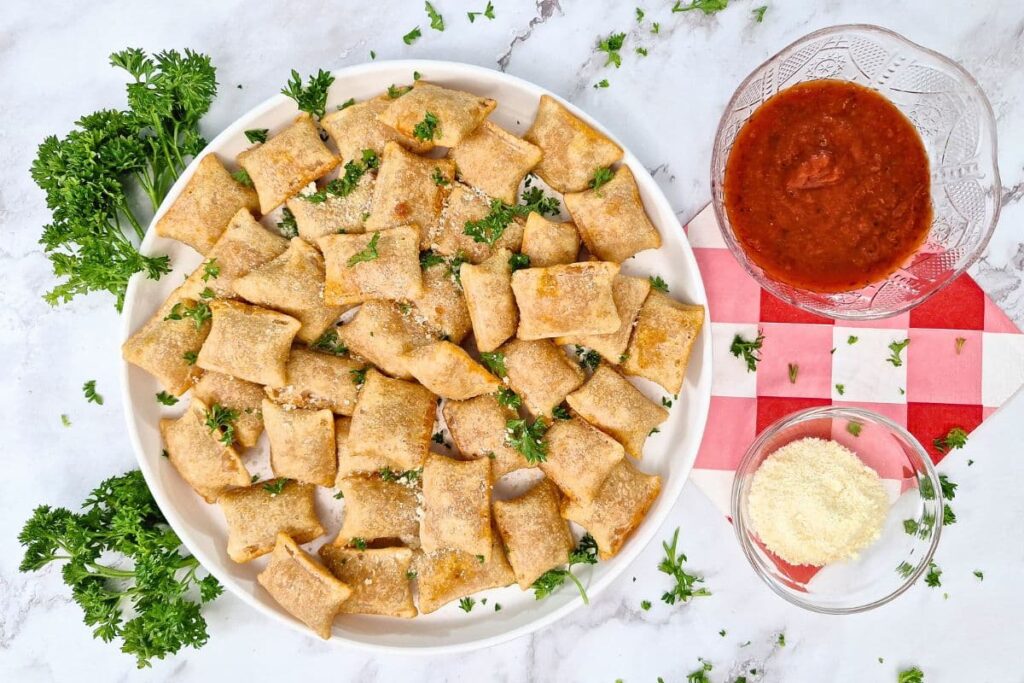 overhead view of a plate of totinos pizza rolls with marinara and parmesan cheese