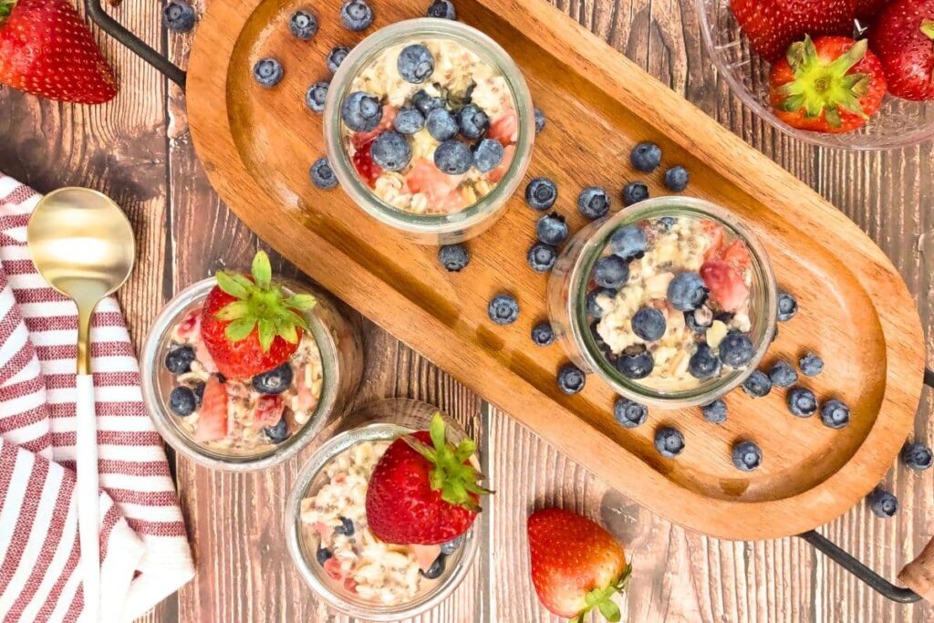 overhead view of strawberry blueberry overnight oats in glasses with fresh fruit