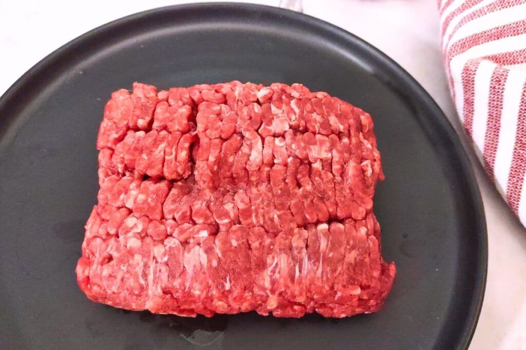 thawed ground beef from the microwave on a black plate