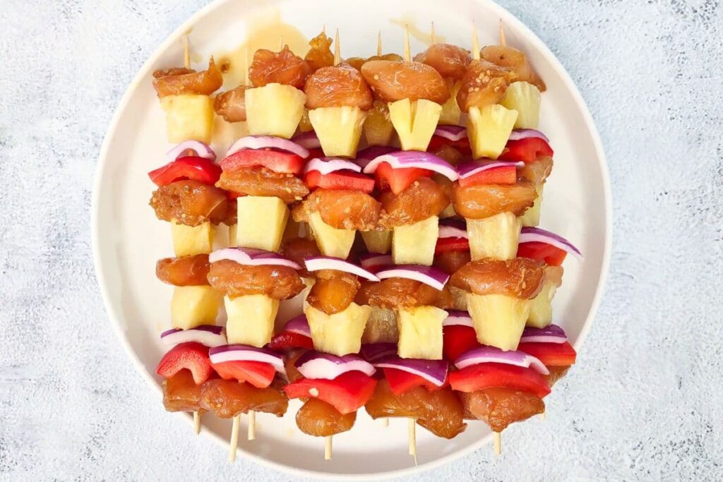 thread chicken pineapple, onion, and pepper on a skewer