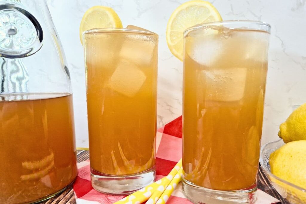 two glasses of ice cold sweet tea vodka lemonade next to a half full pitcher