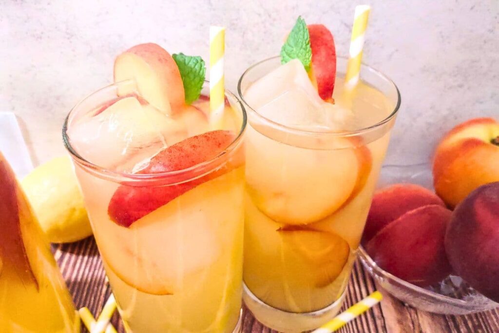 two glasses of peach vodka lemonade and fresh peaches