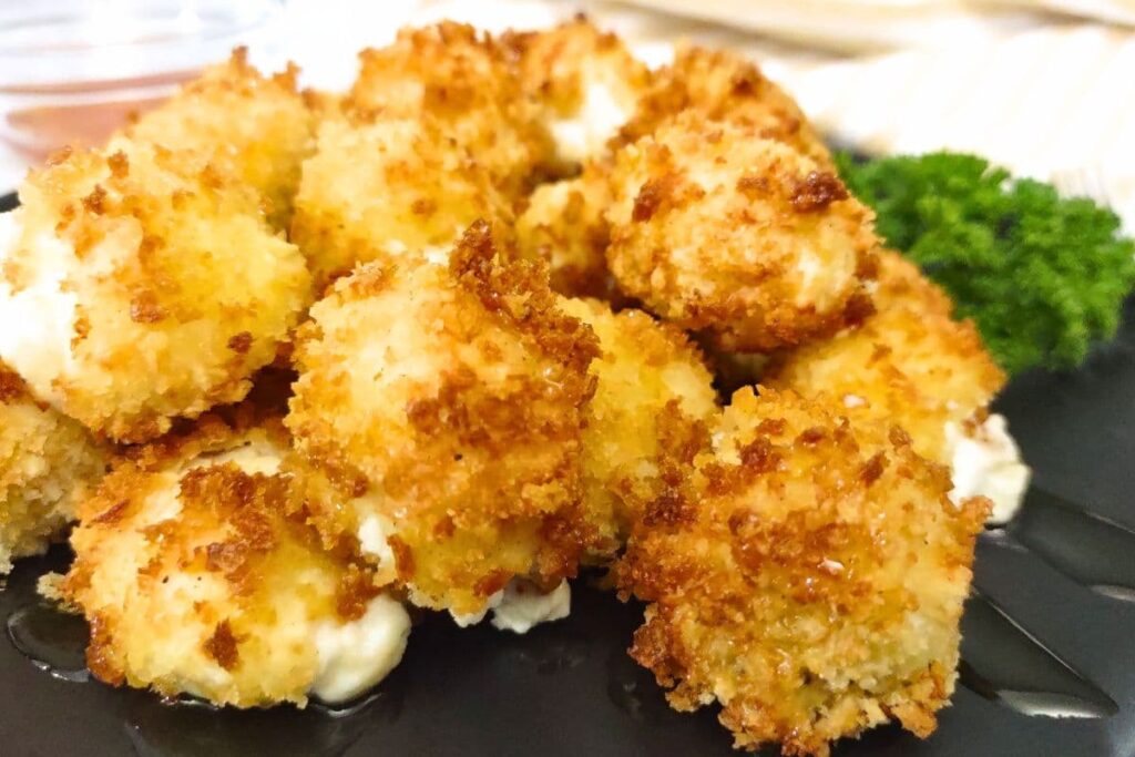 close up of golden browned air fryer goat cheese balls stacked on a plate