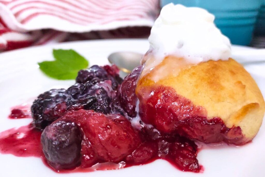 closeup of air fryer mixed berry cobbler on a plate with whipped cream
