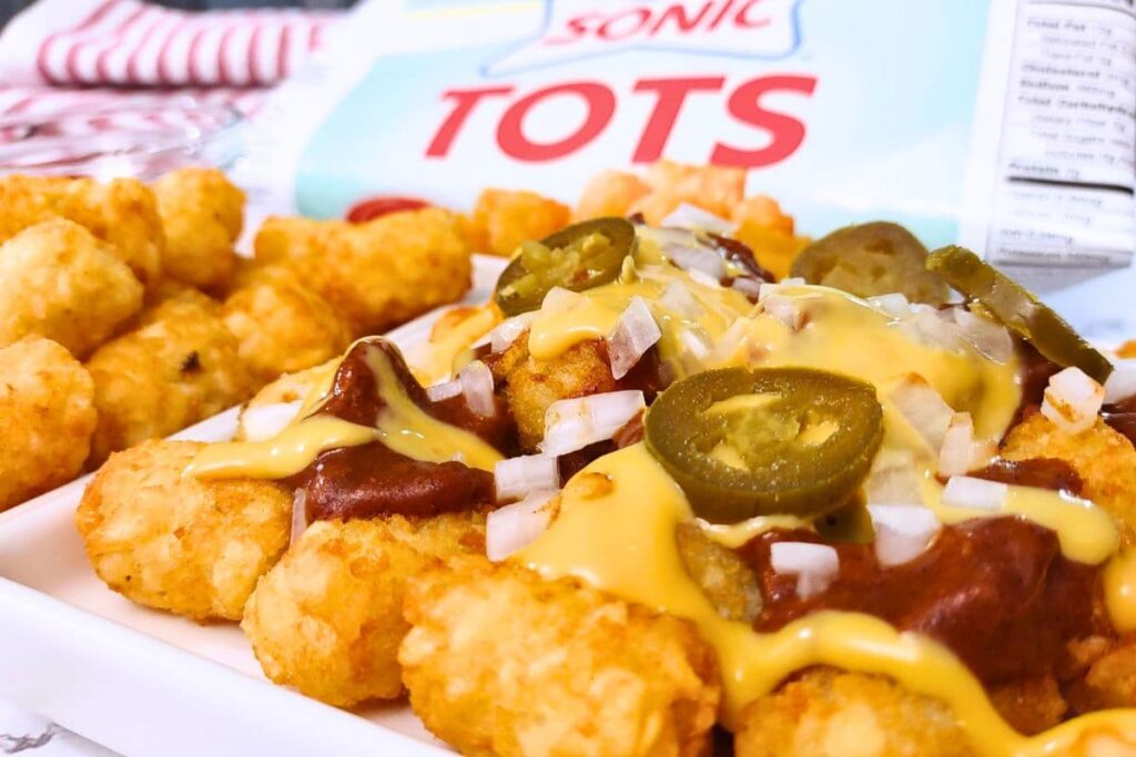 closeup of air fryer sonic tater tots with chili, cheese, onion, and jalapeno