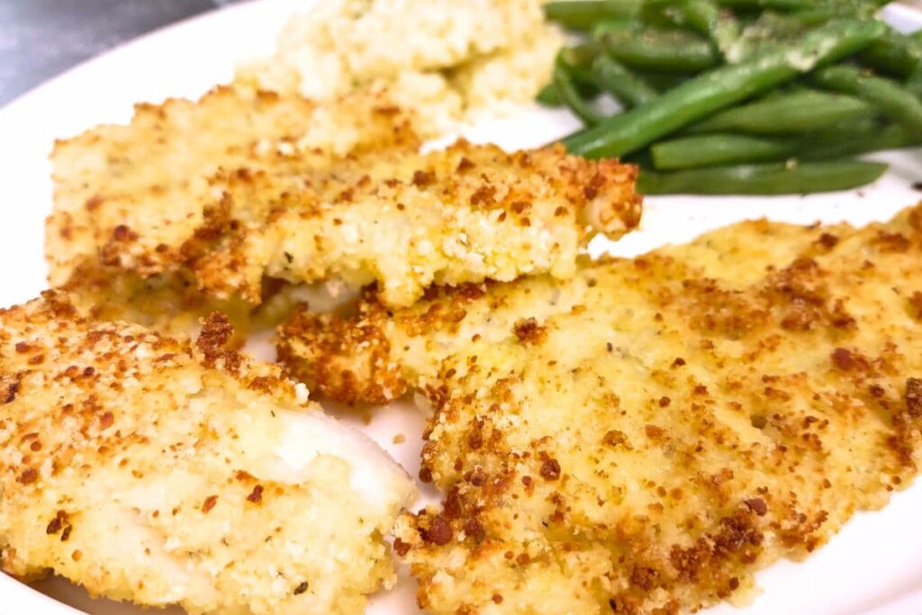 closeup of parmesan crusted cod on a plate with green beans