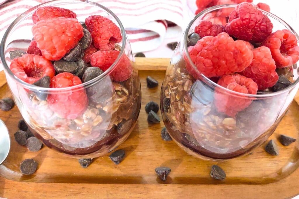 glasses of overnight oats filled with fresh raspberries and chocolate drops