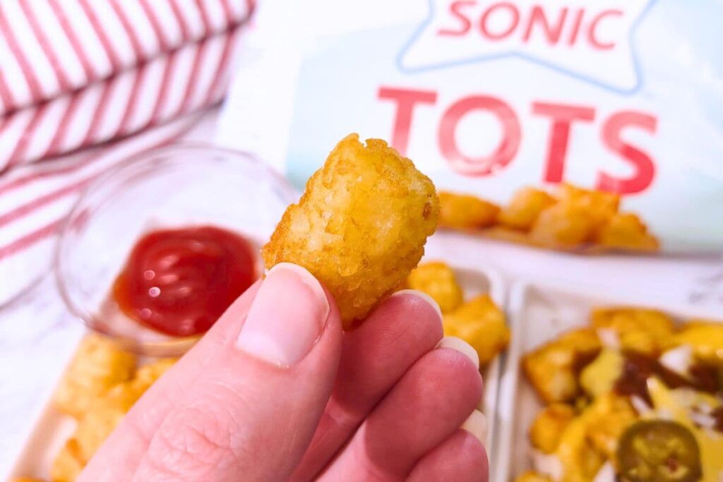 holding up a golden brown air fryer sonic tater tot