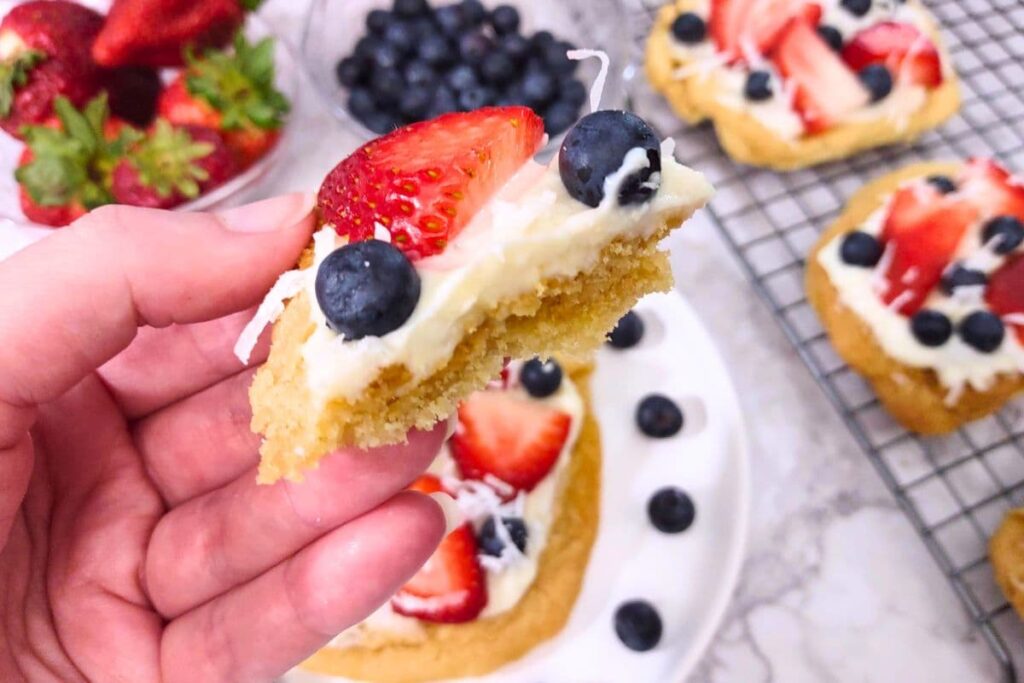 holding up a slice of sugar cookie fruit pizza
