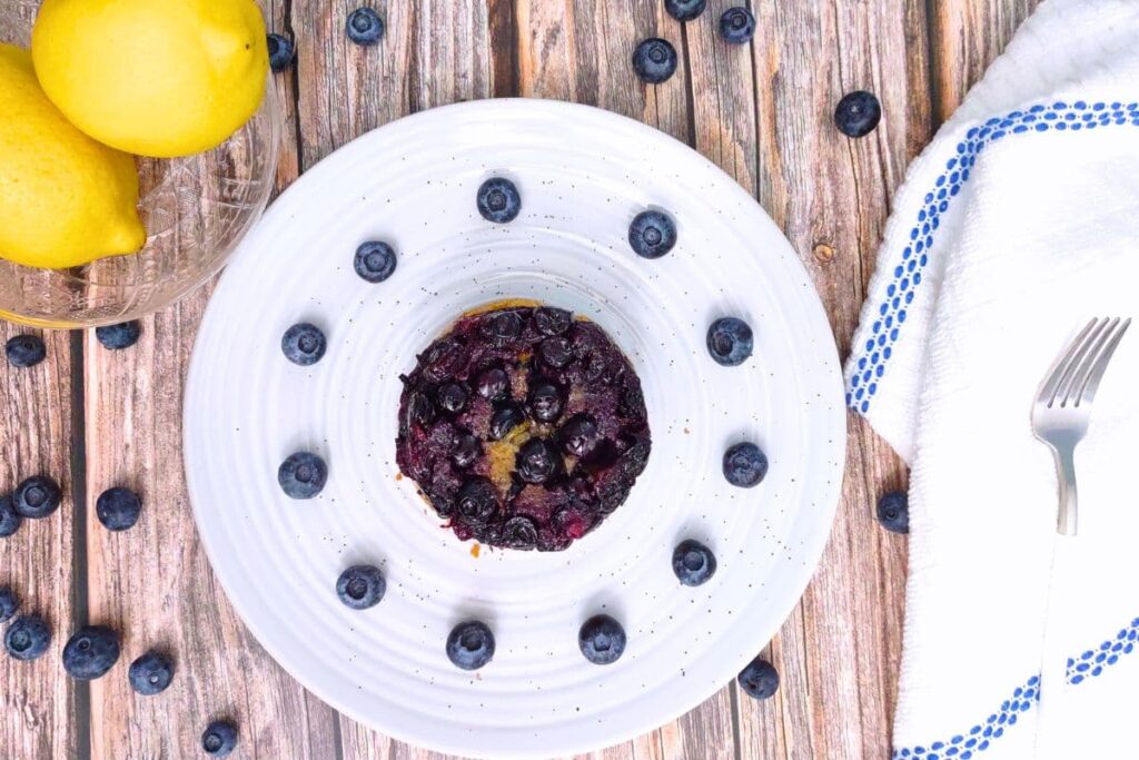 overhead view of air fryer blueberry cake on a plate surrounded by fresh fruit