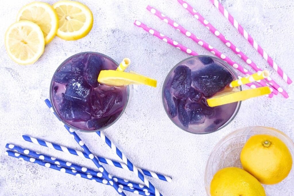 overhead view of two glasses of galaxy lemonade with straws and fresh lemons