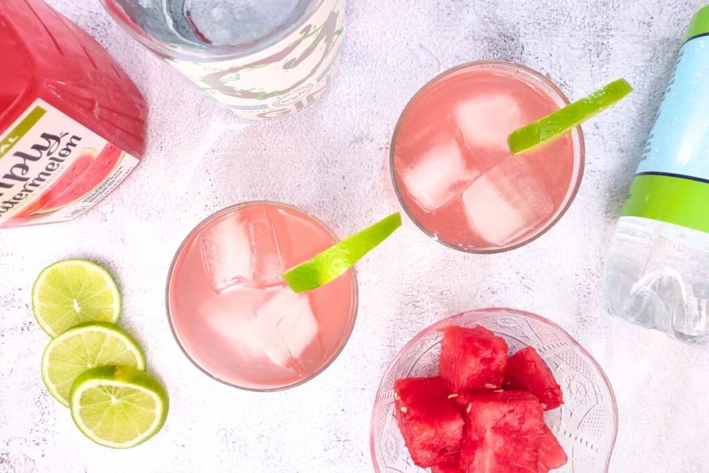 overhead view of two watermelon gin fizz drinks with the bottles in the background