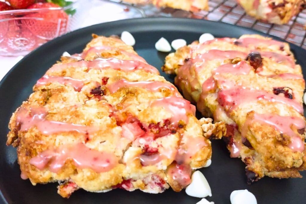 two golden strawberry white chocolate scones cooked in the air fryer on a plate