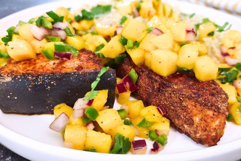 closeup of blackened swordfish steak made in the air fryer topped with jalapeno mango salsa