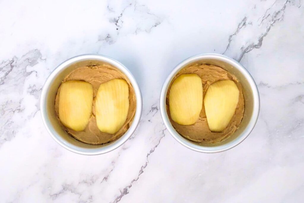 divide batter evenly into cake pans and press apples on top