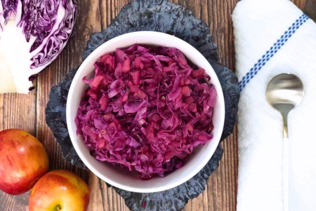 overhead view of microwave red cabbage in a bowl with fresh apples on the side