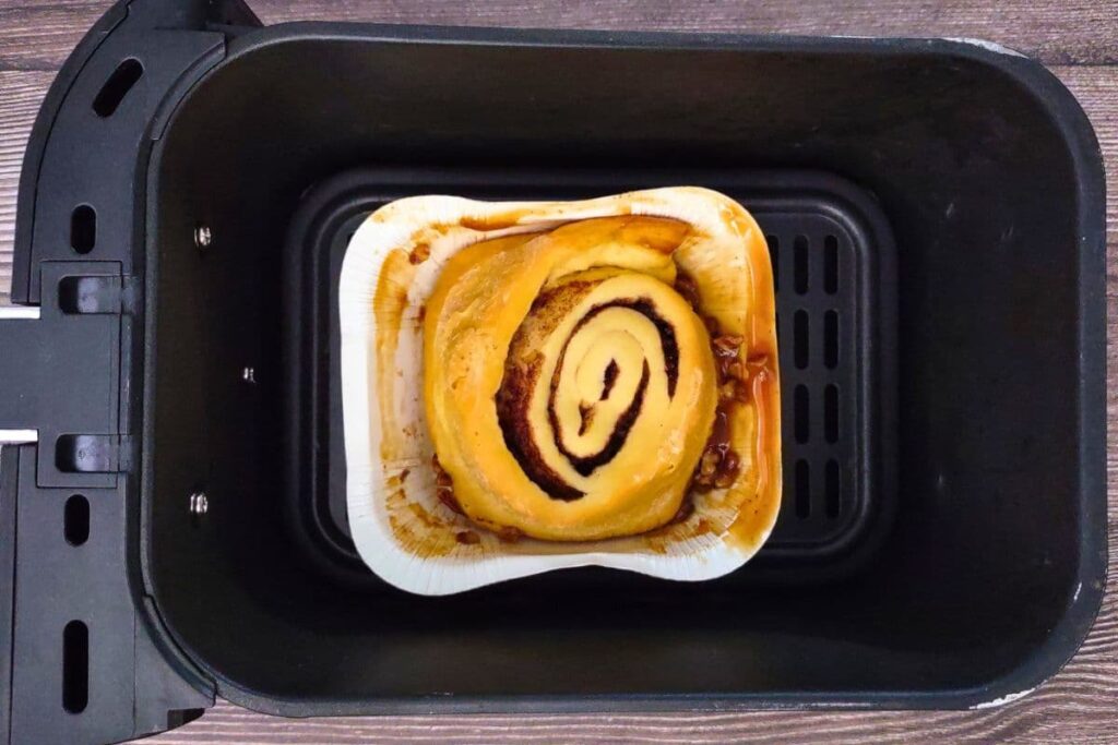 place cinnabon pecan roll in air fryer basket in the container