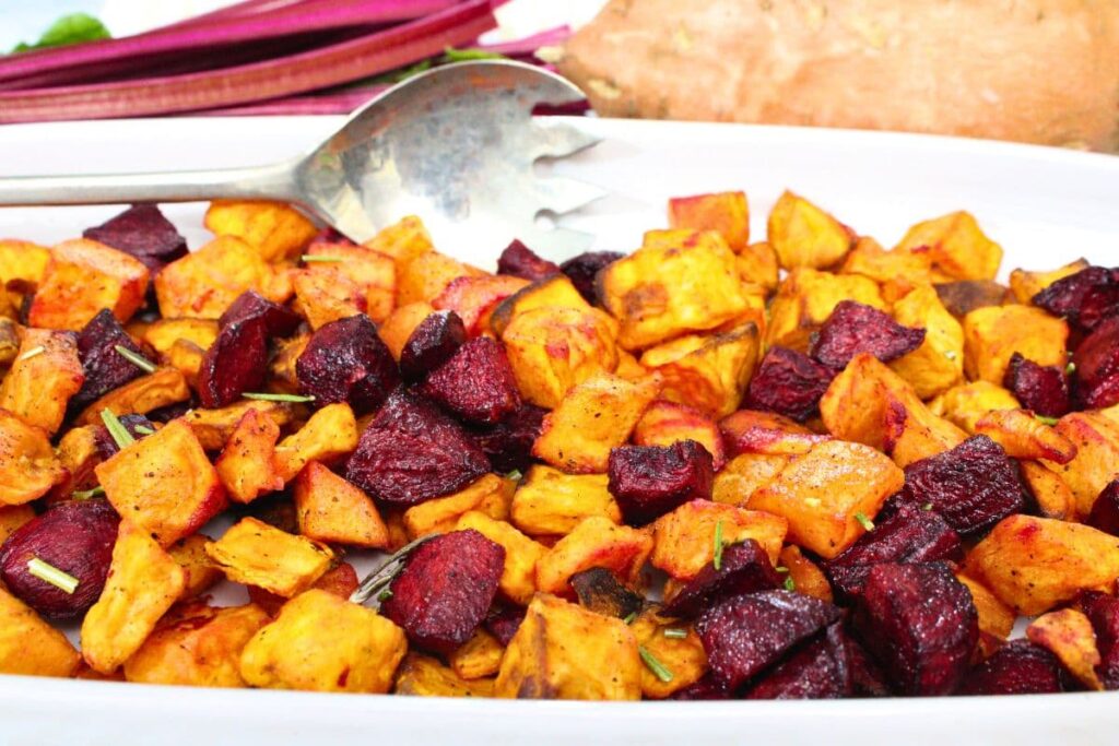 colorful air fryer beets and sweet potatoes on a platter with a serving spoon
