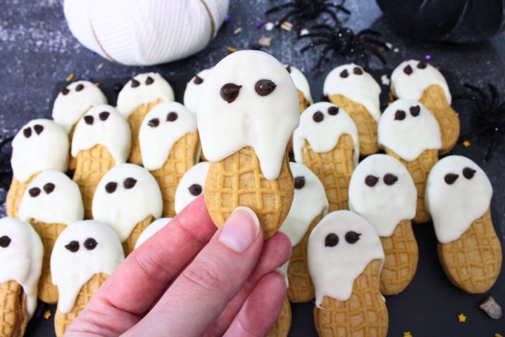 holding up a spooky nutter butter ghost cookie