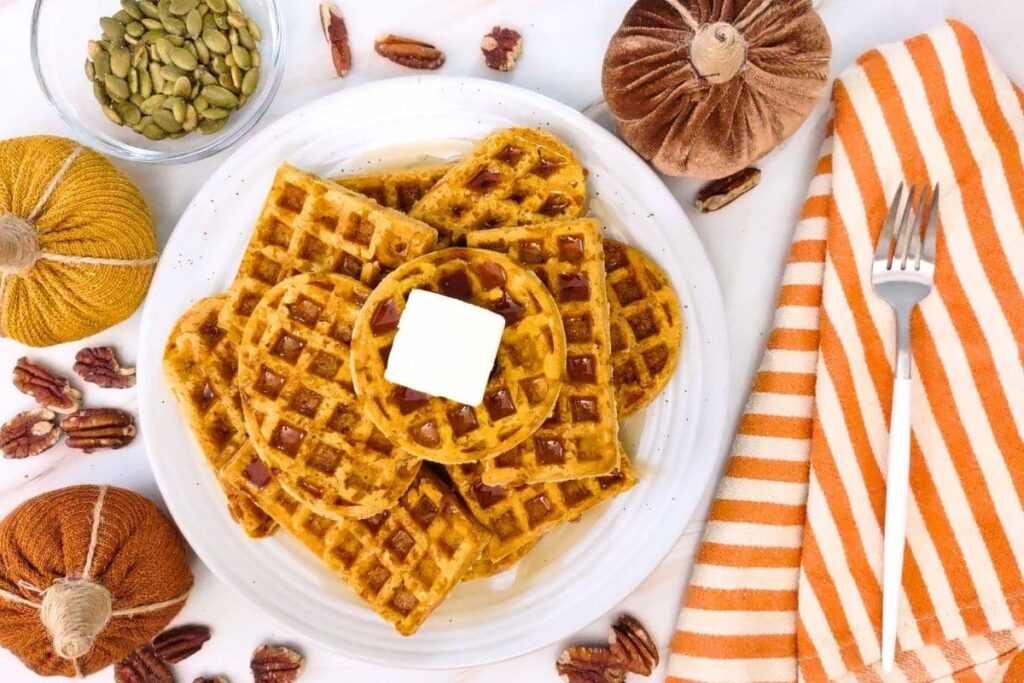 overhead view of stacked up pumpkin waffles on a plate with a pad of butter