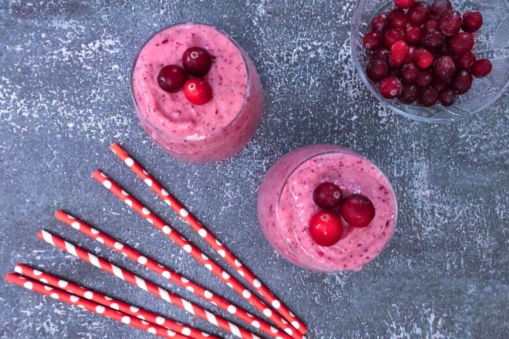 overhead view of two cranberry banana smoothies with striped straws