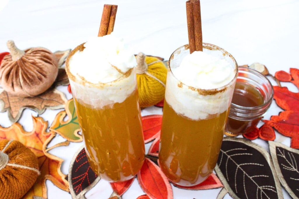 pumpkin spice mimosa glasses with whipped cream and cinnamon sticks