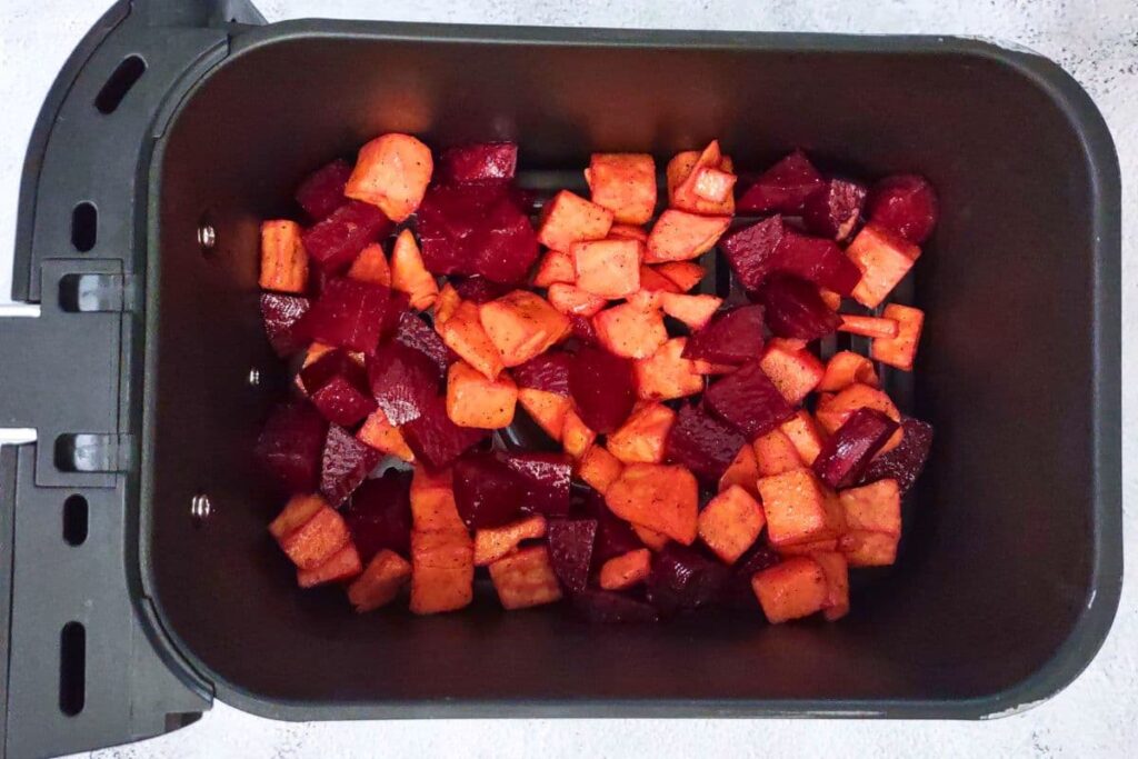 spread beets and sweet potatoes in a layer across the air fryer basket
