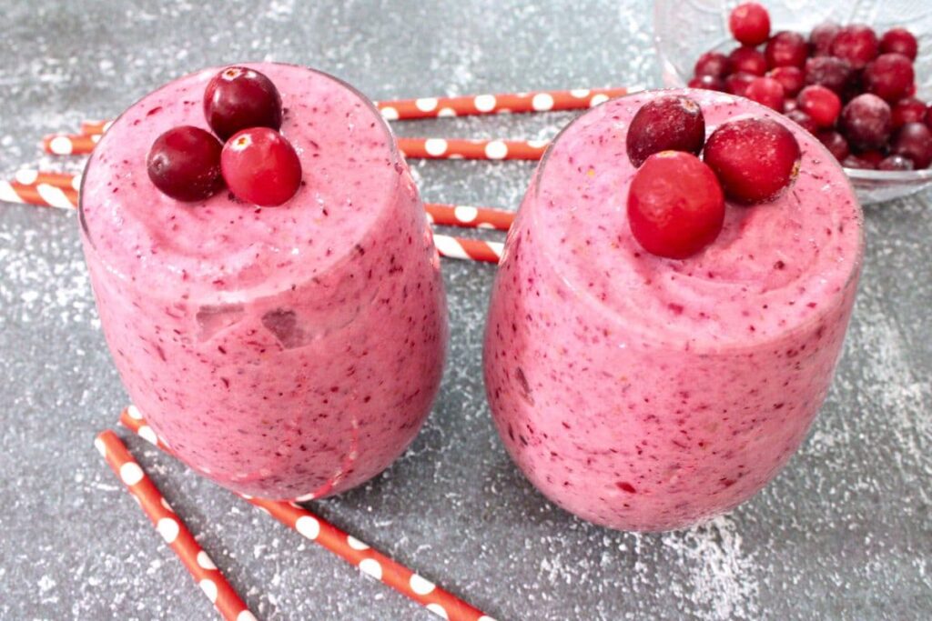 two glasses of cranberry banana smoothie with fresh cranberry on top
