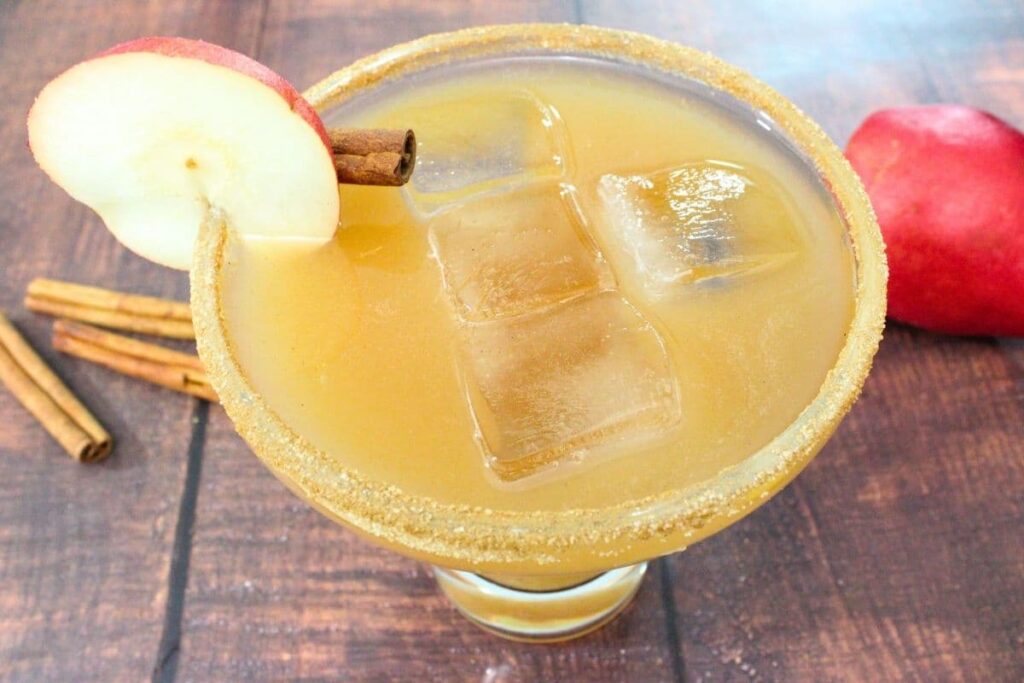 closeup view of spiced pear margarita with a cinnamon stick and pear slice on the rim