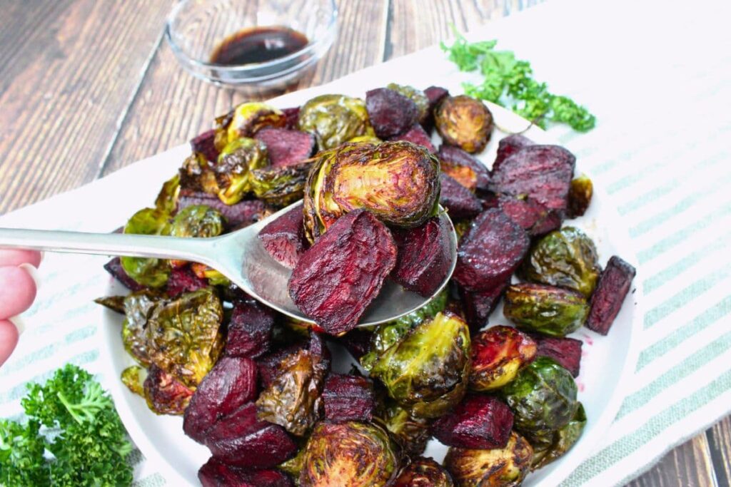 holding up a spoonful of air fryer roasted brussels sprouts and beets