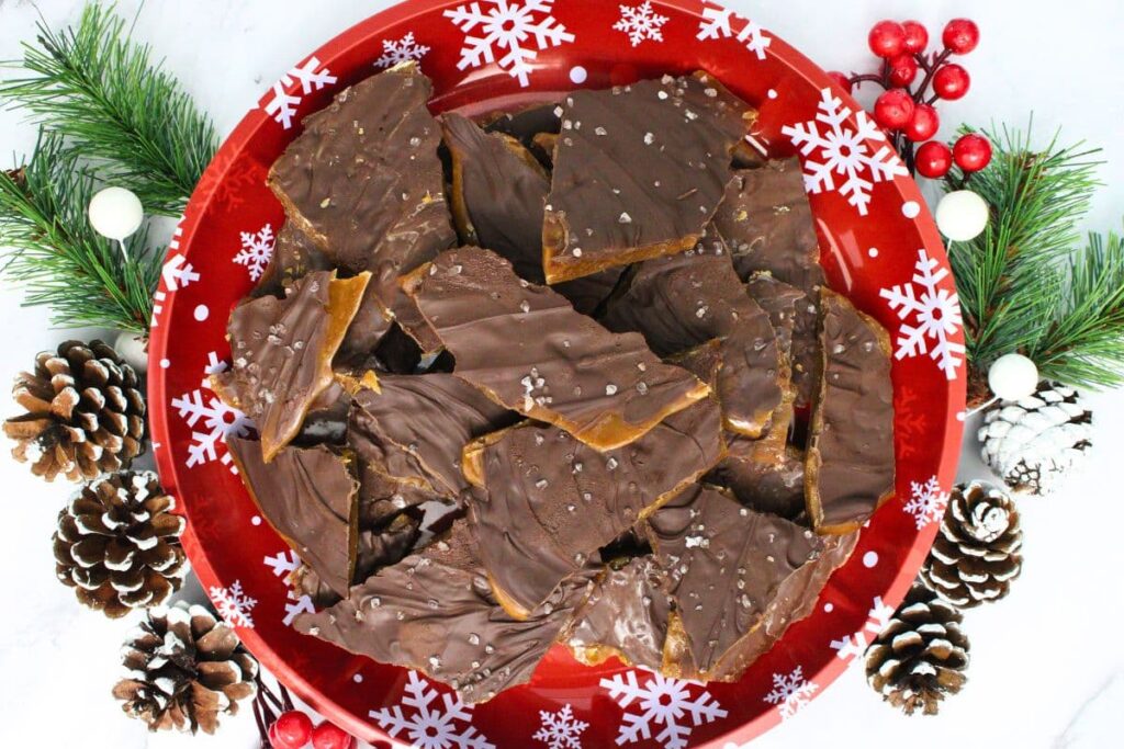 overhead view of microwave toffee on a christmas plate with festive holiday shrubbery
