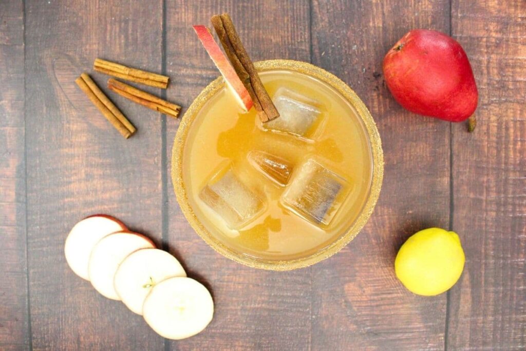 overhead view of spiced pear margarita surrounded by cinnamon sticks and pear slices