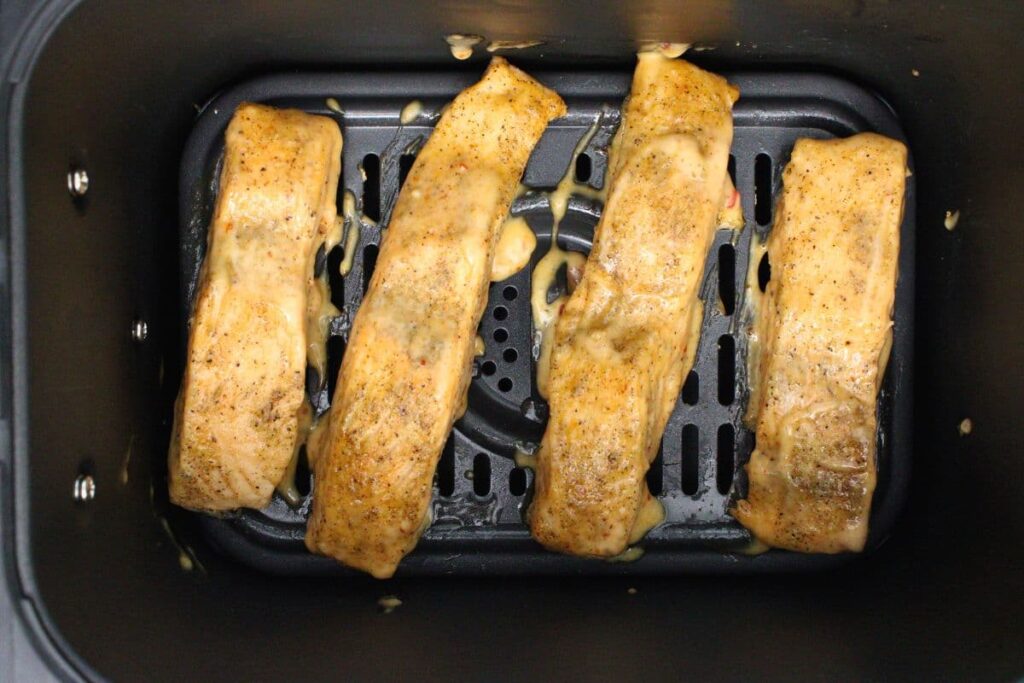 brush the tops of salmon filets with bang bang sauce while in air fryer basket