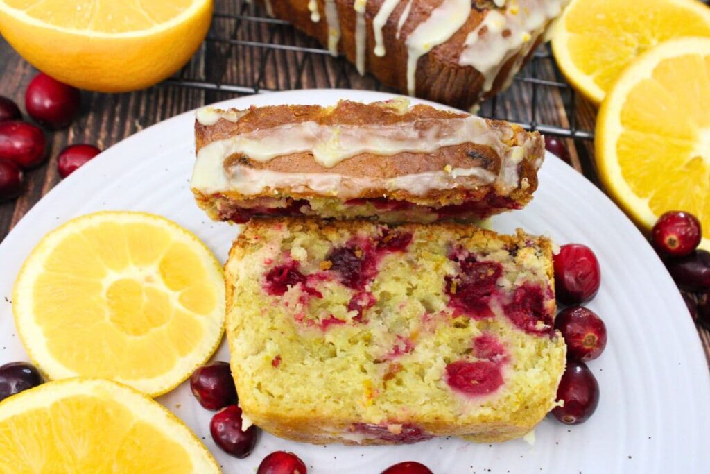 iced cranberry orange bread on a plate with fresh fruit