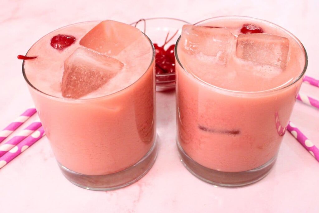 looking down at two pink polar bear cocktails with pink paper straws surrounding