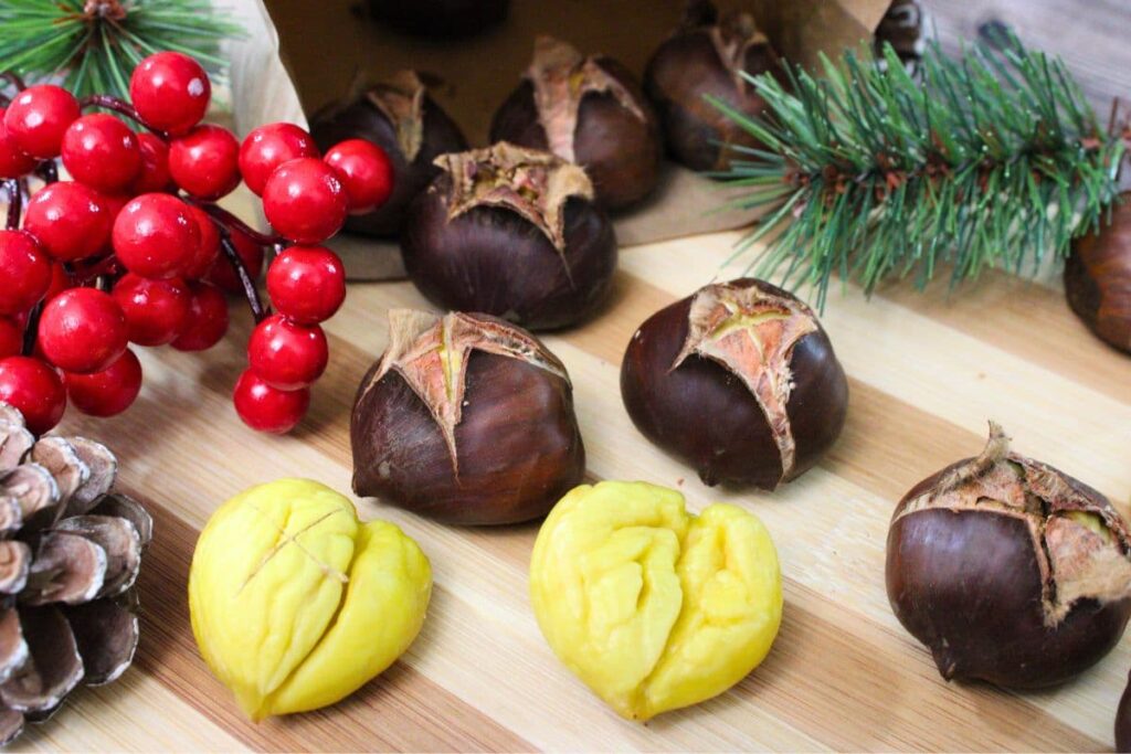 ninja air fryer chestnuts spread out on a wooden cutting board with holiday trimmings