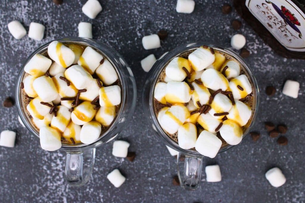 overhead view of two mugs of salted caramel whiskey hot chocolate topped with marshmallows
