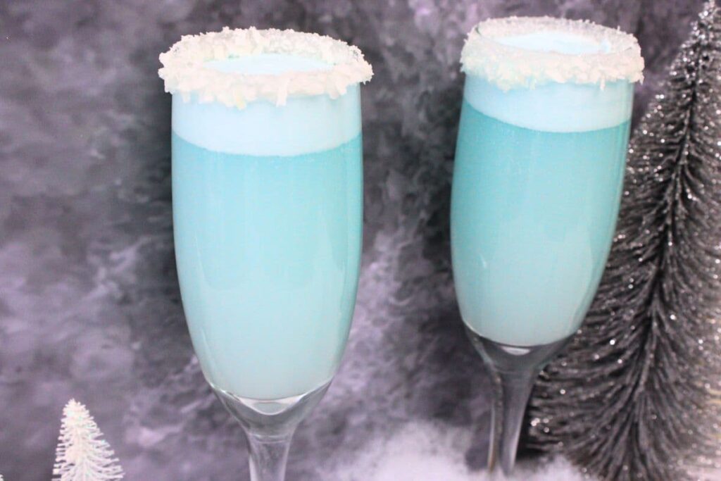 two jack frost mimosas in champagne flutes against a dark background