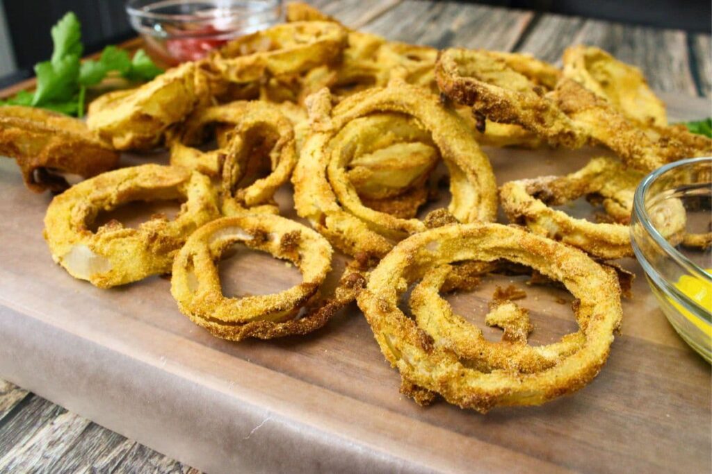 air fryer beer batter onion rings laying across a wooden cutting board