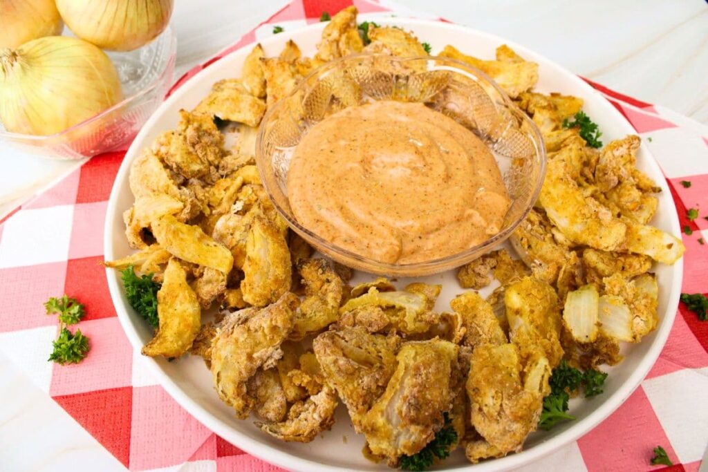 easy air fryer blooming onion petals surrounding a bowl of dip on a plate