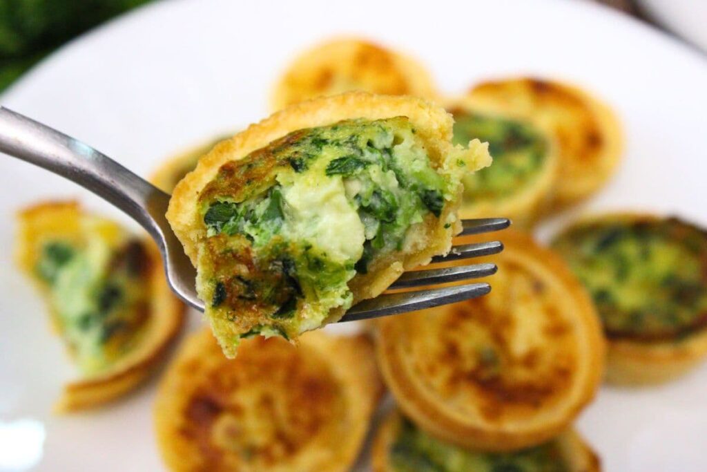 half of an air fryer frozen spinach quiche held up on a fork