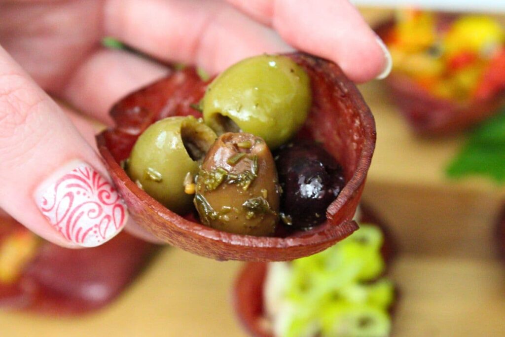 holding up a salami cup filled with italian olive medley