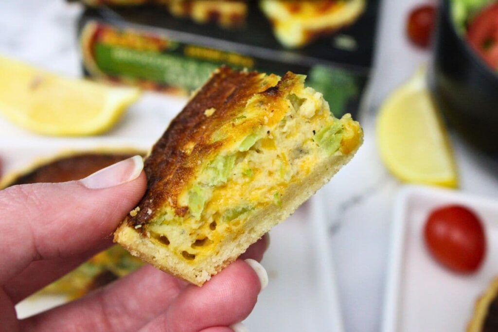 holding up a slice of trader joes broccoli cheddar quiche