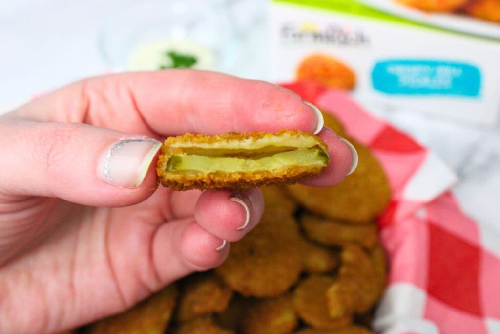 holding up half of an air fryer frozen fried pickle to show the inside