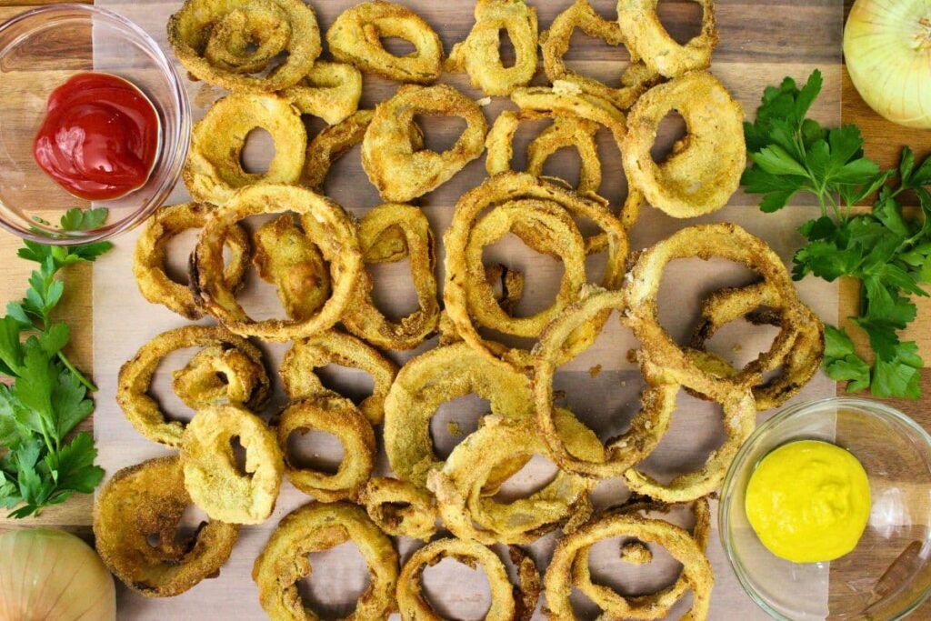 overhead view of air fryer beer battered onion rings on a wooden board