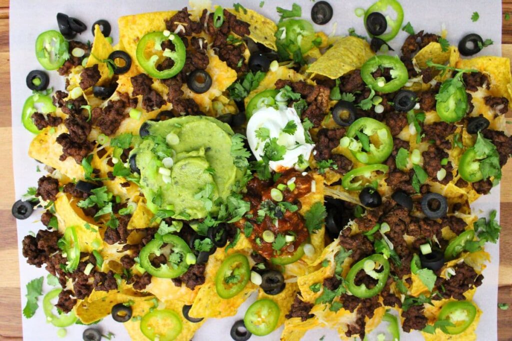 overhead view of air fryer nachos with ground beef, guacamole, and sour cream