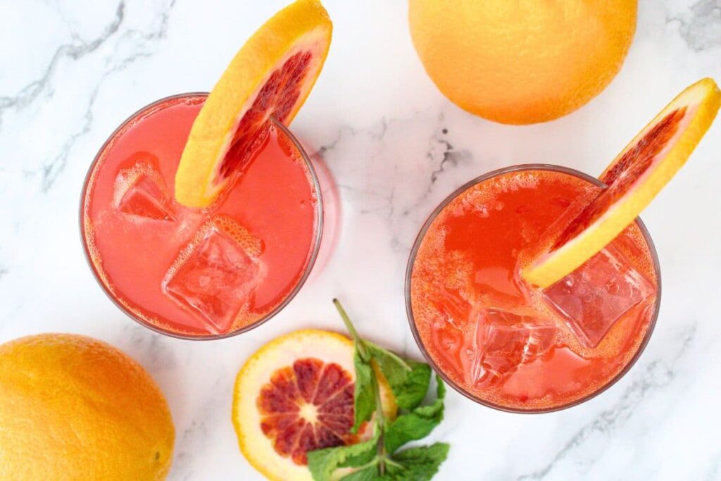 overhead view of two glasses filled with blood orange gin fizz and orange slices