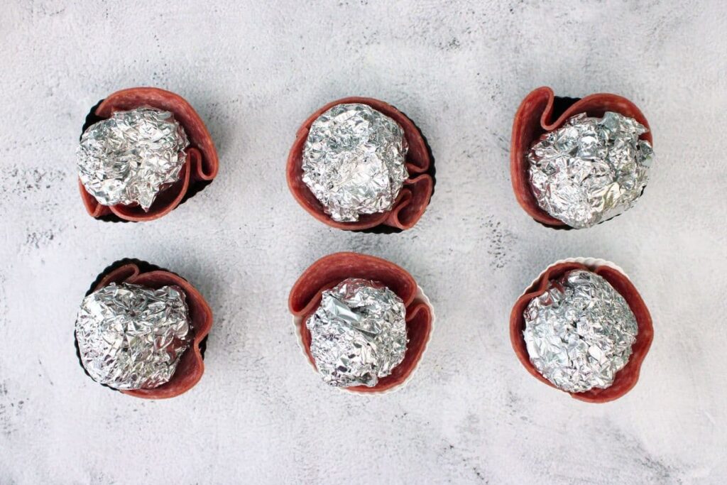 place salami in muffin wrappers and add foil ball to help with shape