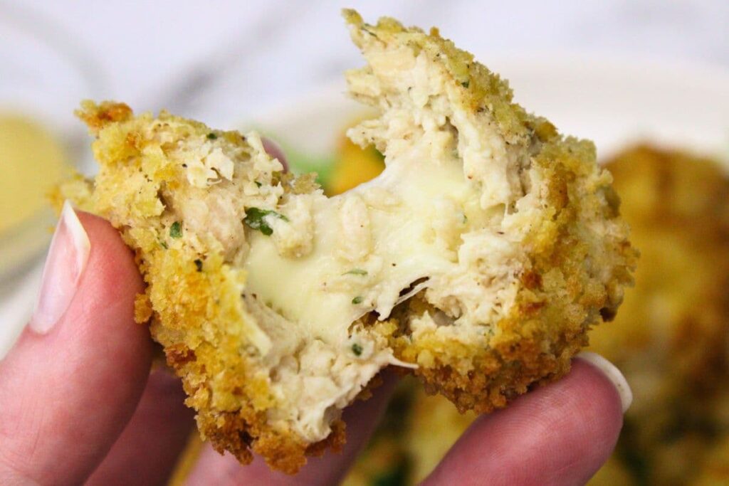 splitting apart an air fryer chicken croquette with a gooey cheese pull