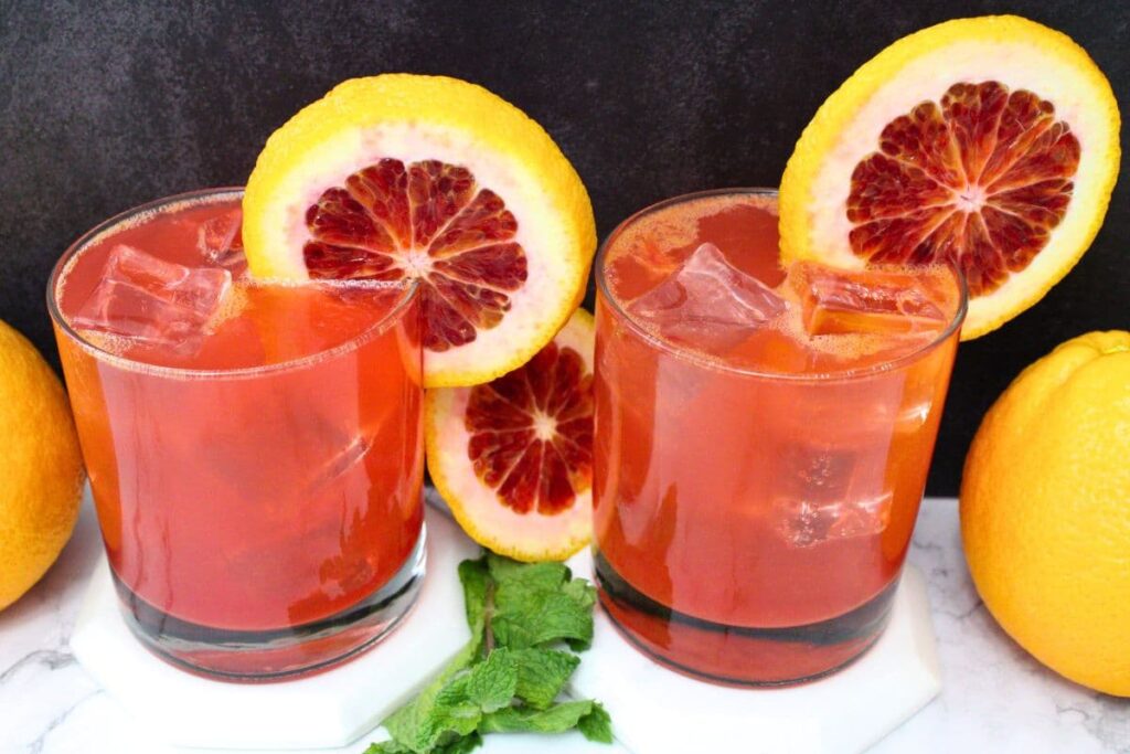two blood orange gin fizz cocktails with blood orange slices in the rim